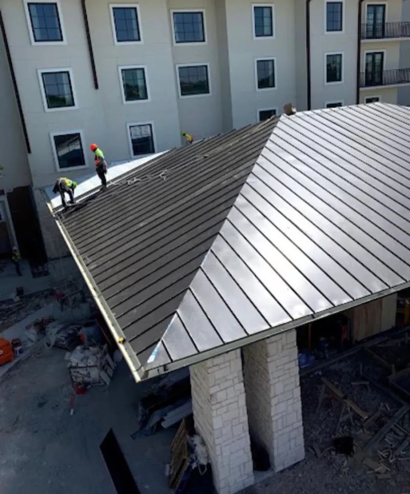Crew installing standing seam metal roof panels on a commercial project in Oscoda